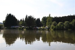 Opposite pond shore with forest and caravans