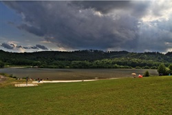 Pond under dark clouds with grass on the shore