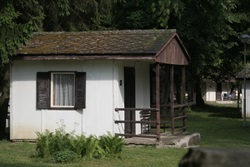 White cabin with a brown roof and porch